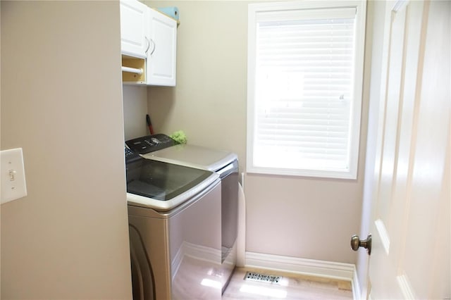 laundry room featuring washing machine and clothes dryer and cabinets