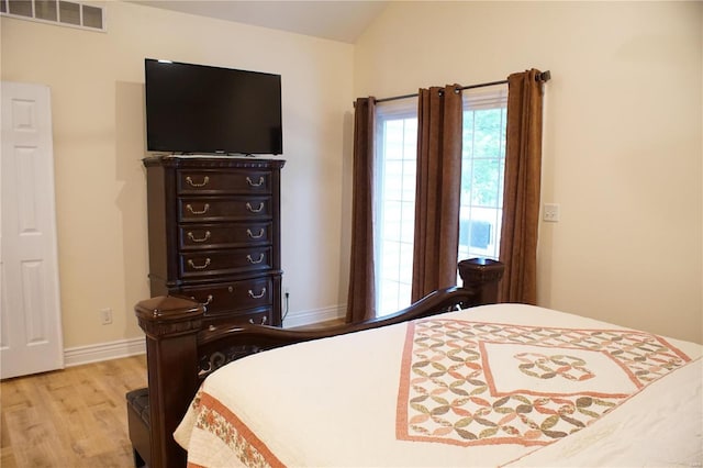 bedroom with light wood-type flooring and vaulted ceiling