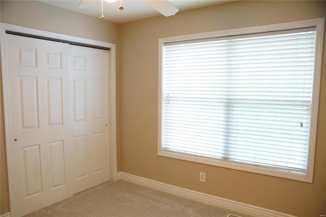 unfurnished bedroom with light carpet, a closet, and ceiling fan