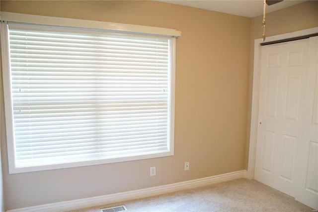 unfurnished bedroom with light colored carpet and a closet