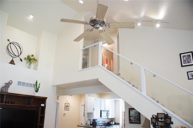 interior space featuring a towering ceiling, rail lighting, and sink