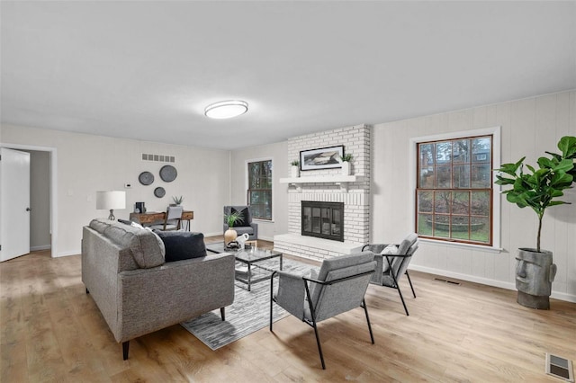 living room featuring a brick fireplace and light wood-type flooring