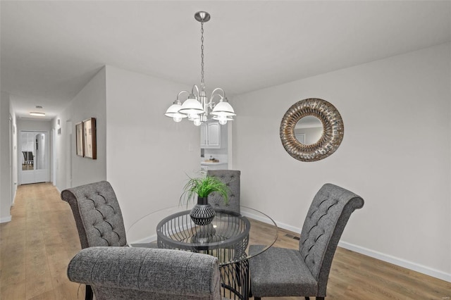 dining area with wood-type flooring and an inviting chandelier