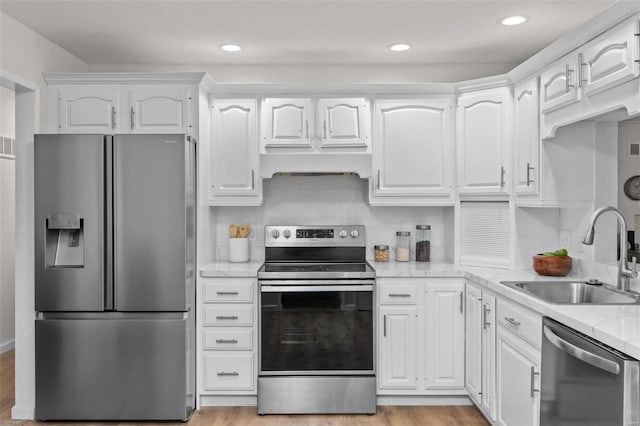 kitchen featuring stainless steel appliances, light stone countertops, sink, and white cabinets