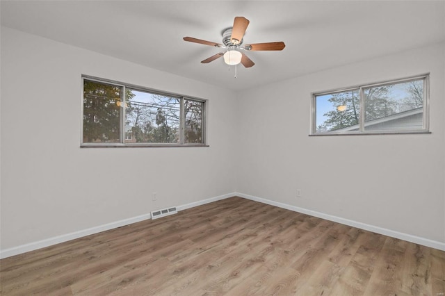 empty room with wood-type flooring, a wealth of natural light, and ceiling fan