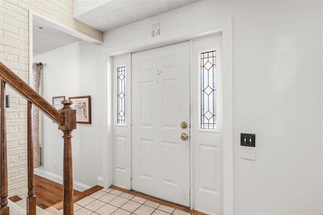 foyer entrance with light wood finished floors, stairway, beam ceiling, and baseboards