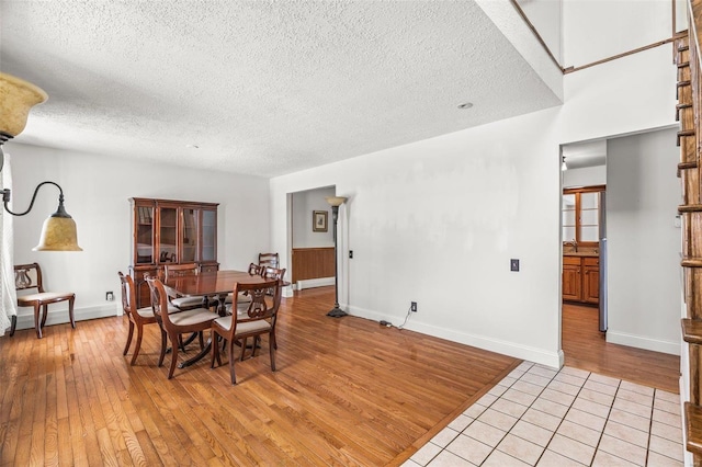 dining space featuring light wood-style floors, baseboards, and a textured ceiling