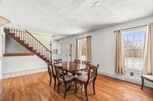 dining area featuring a textured ceiling, stairs, baseboards, and hardwood / wood-style floors