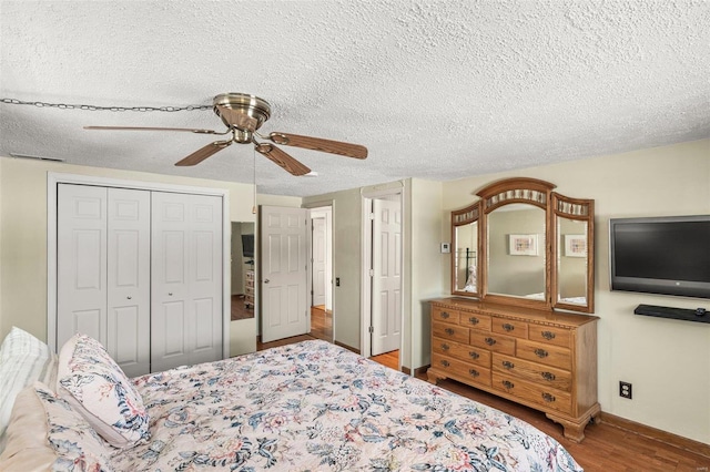 bedroom with a closet, ceiling fan, a textured ceiling, wood finished floors, and baseboards