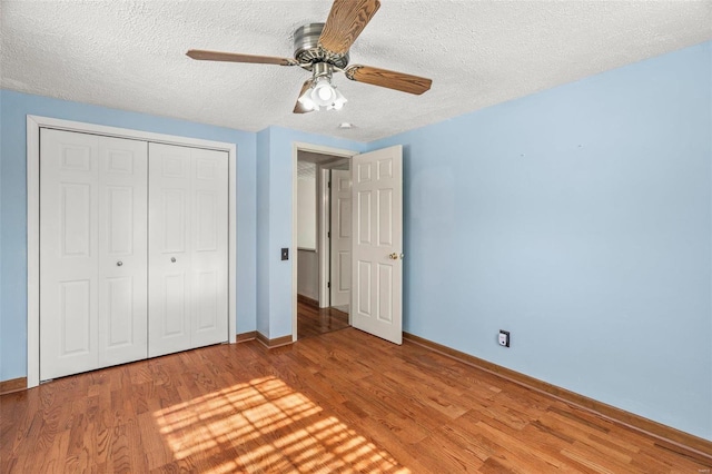 unfurnished bedroom with baseboards, a ceiling fan, a textured ceiling, light wood-type flooring, and a closet