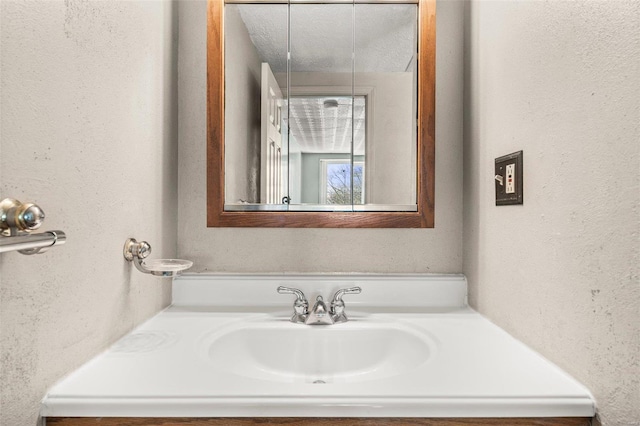 bathroom with a textured wall, vanity, and a textured ceiling