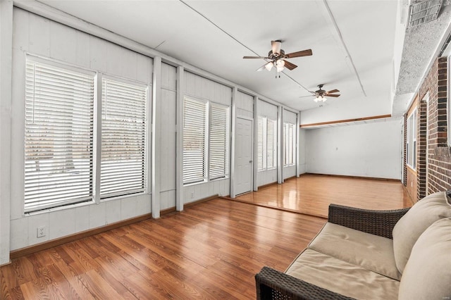 living area with a ceiling fan, a wealth of natural light, baseboards, and wood finished floors