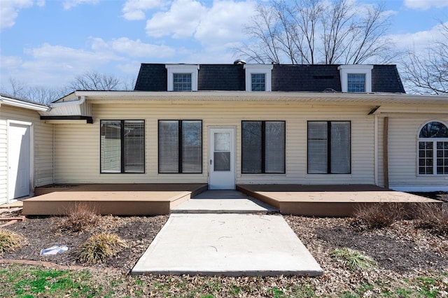 back of property with mansard roof, roof with shingles, and a wooden deck