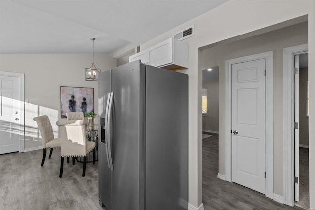 kitchen with wood finished floors, visible vents, white cabinets, baseboards, and stainless steel fridge with ice dispenser