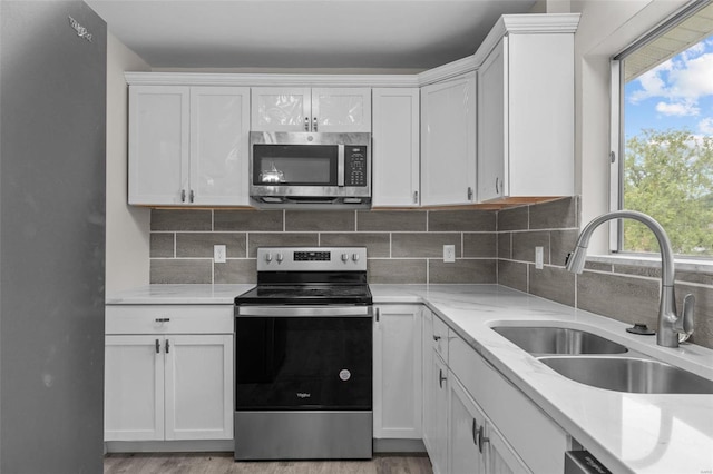 kitchen featuring stainless steel appliances, white cabinets, a sink, and decorative backsplash