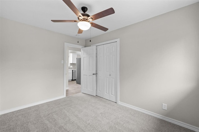 unfurnished bedroom with a ceiling fan, a closet, light carpet, and baseboards