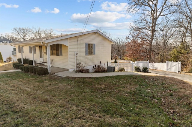 view of side of property with a gate, covered porch, a lawn, and fence