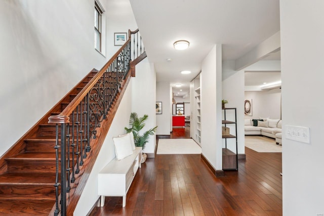 entryway featuring dark wood-style flooring, baseboards, and stairs