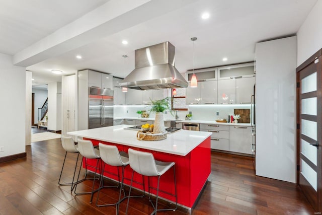 kitchen with white cabinets, appliances with stainless steel finishes, decorative light fixtures, island exhaust hood, and light countertops