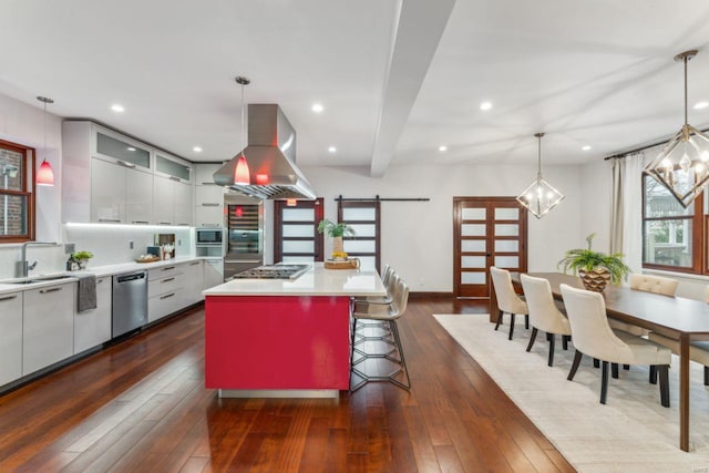 kitchen with a barn door, glass insert cabinets, a center island, island exhaust hood, and light countertops