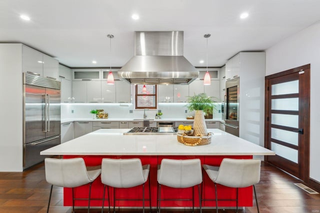 kitchen featuring light countertops, appliances with stainless steel finishes, modern cabinets, island exhaust hood, and decorative light fixtures