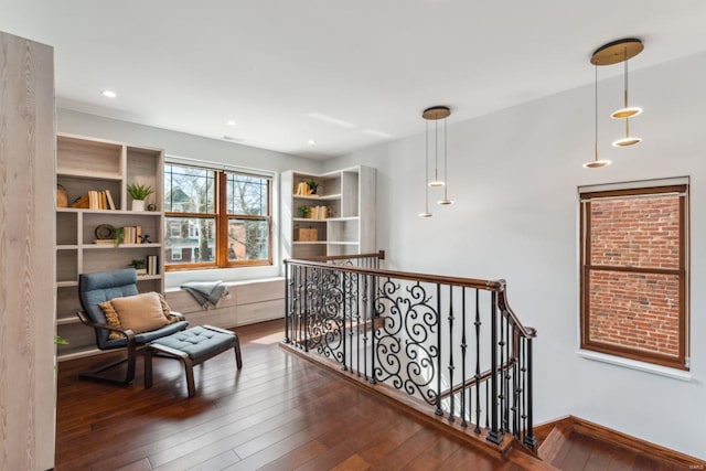 sitting room featuring dark wood-type flooring, recessed lighting, and an upstairs landing