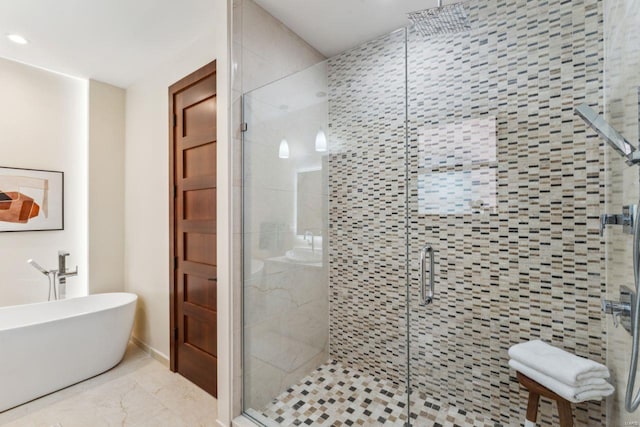 full bathroom featuring marble finish floor, a shower stall, and a freestanding tub