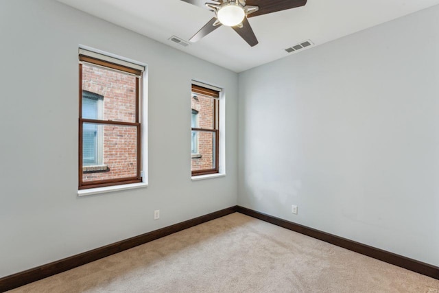 empty room featuring a ceiling fan, visible vents, light carpet, and baseboards