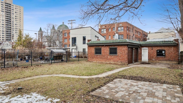 back of house featuring brick siding, a lawn, a patio area, and fence