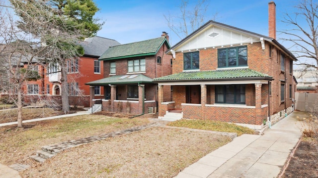 view of front facade with a chimney, fence, a porch, and brick siding