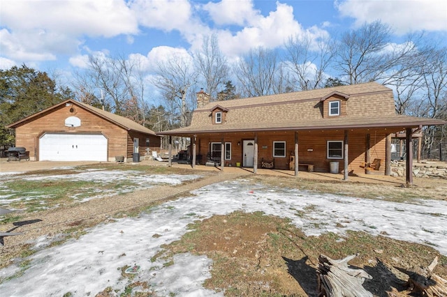 view of front of property with covered porch, a garage, and an outdoor structure