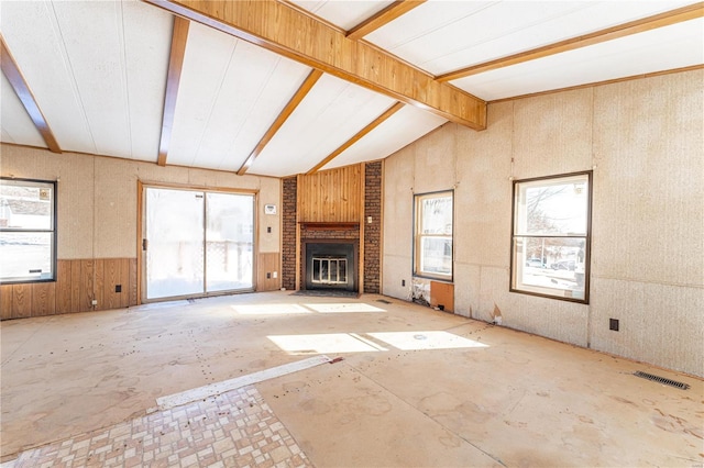 unfurnished living room with a fireplace, lofted ceiling with beams, and plenty of natural light