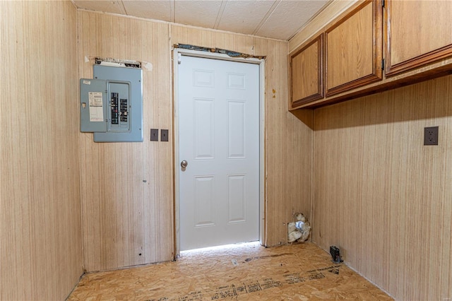 washroom featuring electric panel, cabinets, and wood walls