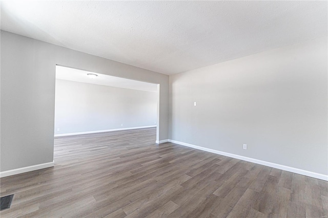 empty room with hardwood / wood-style floors and a textured ceiling