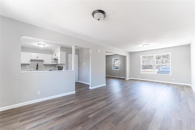 unfurnished living room featuring dark hardwood / wood-style floors, sink, and a textured ceiling