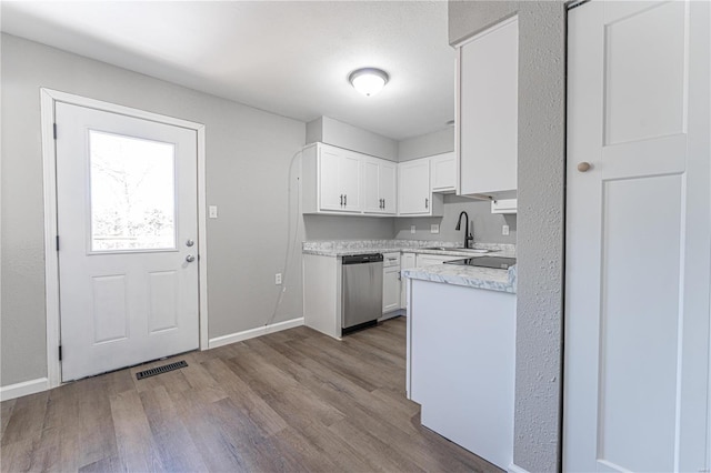 kitchen featuring white cabinetry, sink, stainless steel dishwasher, and light hardwood / wood-style flooring