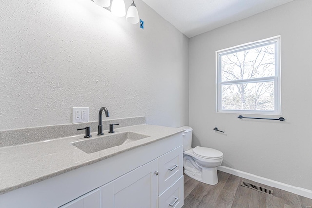 bathroom with wood-type flooring, toilet, and vanity