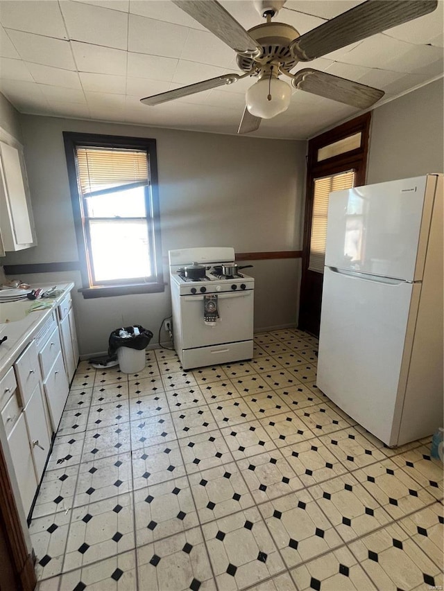 kitchen with white appliances, ceiling fan, and white cabinets