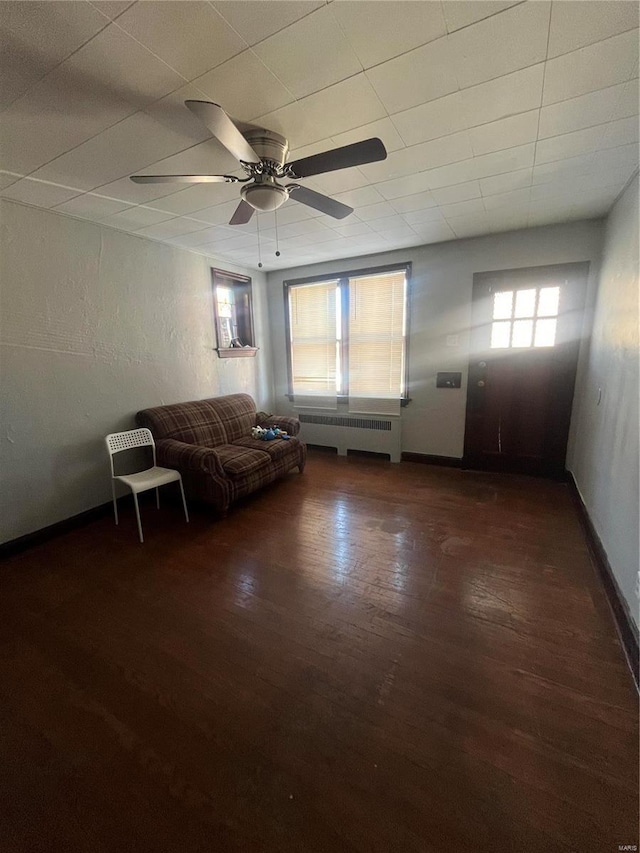 unfurnished living room featuring radiator, ceiling fan, and dark wood-type flooring