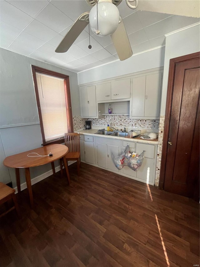 kitchen featuring dark wood-type flooring, backsplash, white cabinets, ceiling fan, and sink