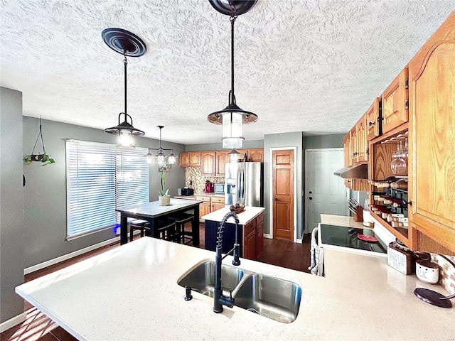 kitchen with stainless steel refrigerator with ice dispenser, sink, pendant lighting, and kitchen peninsula