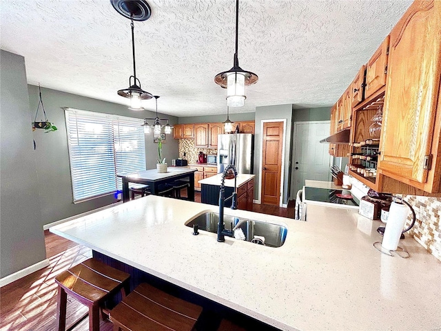 kitchen featuring a kitchen island, decorative light fixtures, sink, stainless steel fridge with ice dispenser, and kitchen peninsula