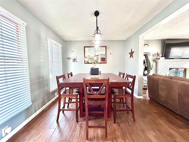 dining space featuring a textured ceiling, dark hardwood / wood-style floors, and a fireplace