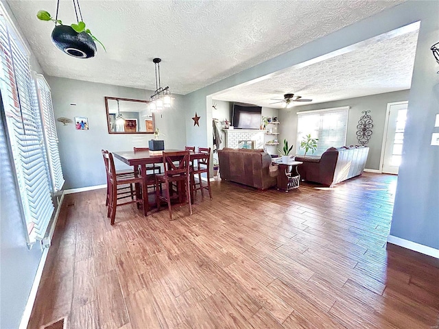 dining space with hardwood / wood-style flooring, a textured ceiling, and ceiling fan with notable chandelier