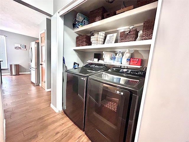 laundry room featuring a textured ceiling, light hardwood / wood-style flooring, and washing machine and clothes dryer