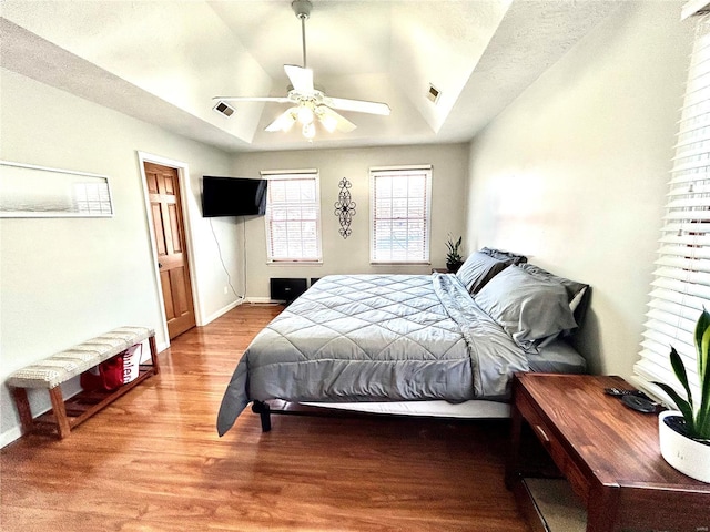 bedroom featuring vaulted ceiling, ceiling fan, hardwood / wood-style flooring, and a tray ceiling