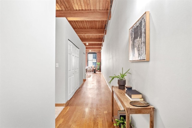 hallway with beam ceiling, wood ceiling, and light hardwood / wood-style flooring