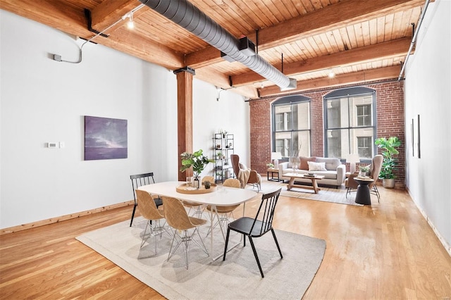 dining space with beam ceiling, light wood-type flooring, brick wall, and wooden ceiling