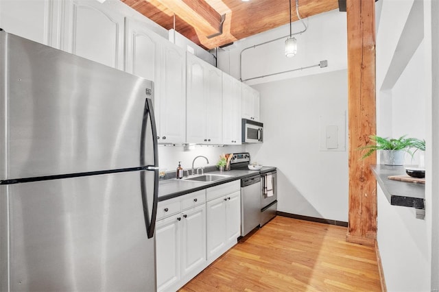 kitchen featuring appliances with stainless steel finishes, light wood-type flooring, sink, pendant lighting, and white cabinets