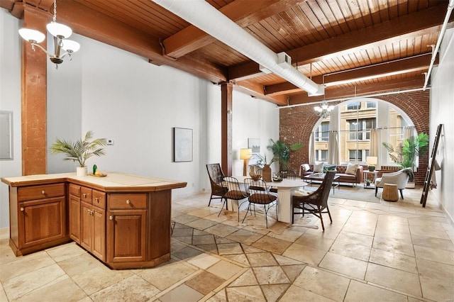 dining space featuring beam ceiling, wood ceiling, brick wall, and an inviting chandelier